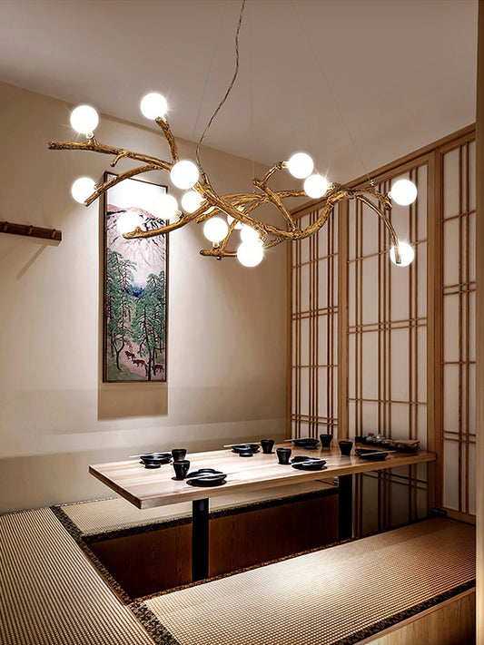 Modern interior design with a chandelier resembling branches, a dining table, and a wall painting.