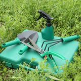 Set of gardening tools including a trowel, pruner, and sprayer on a green case in grass.