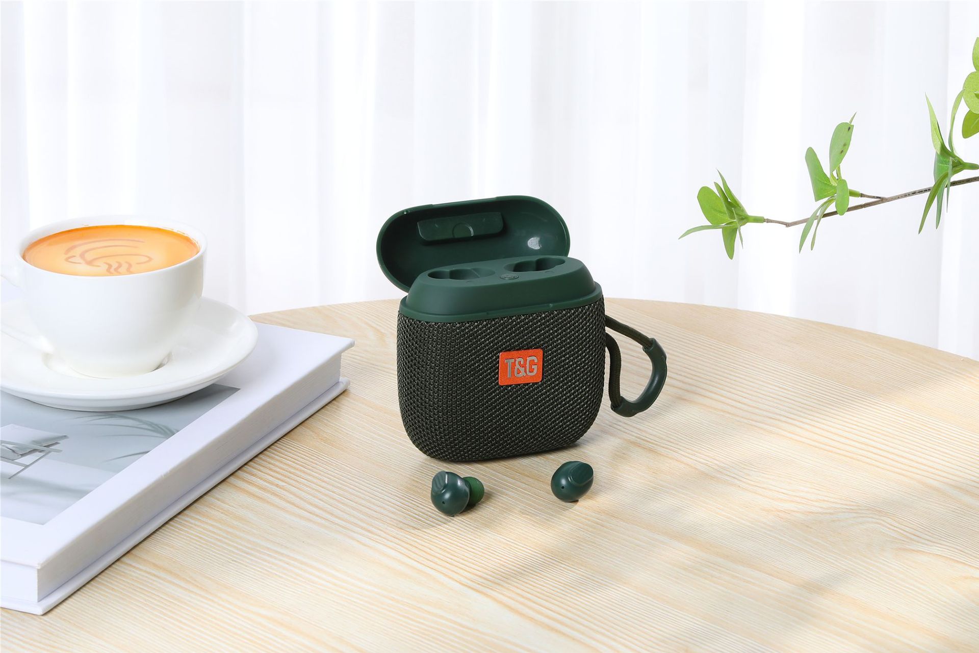 Green wireless earbuds case with JBL logo on a wooden table with a cup of coffee and book in the background.