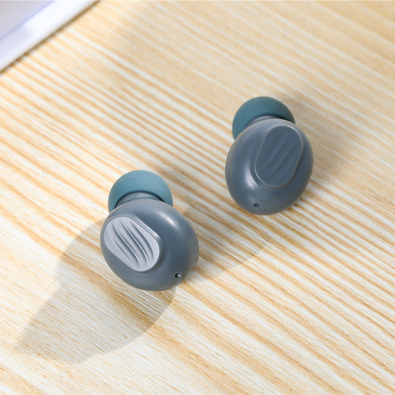 Pair of gray wireless earbuds on a wooden surface