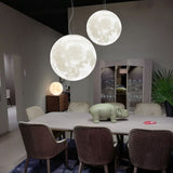 Dining room with large moon-shaped pendant lights hanging above a table.