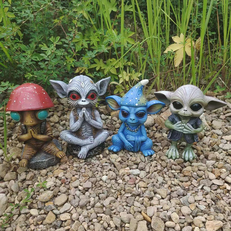 Four small figurines with unique designs on a pebble surface with greenery in the background