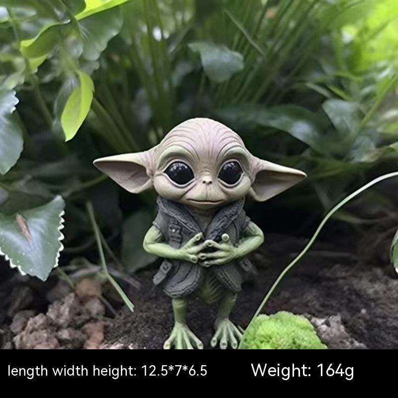 Toy figure of a character with large ears and a green outfit, surrounded by leaves.