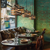 Dining area with round tables, chairs, and decorative lighting fixture in a restaurant.