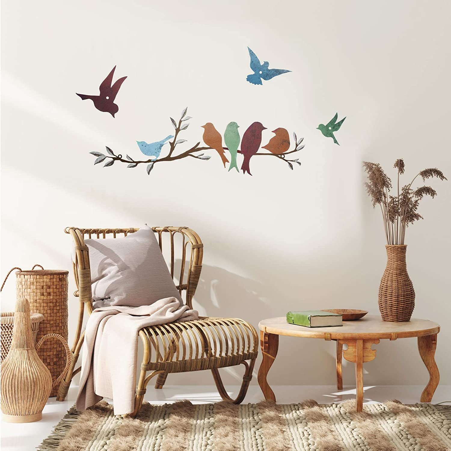 Decorative wall stickers of birds on a branch in a living room setting with a wicker chair and wooden table.