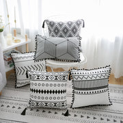 Black and white patterned pillows on a chair and floor in a room setting.