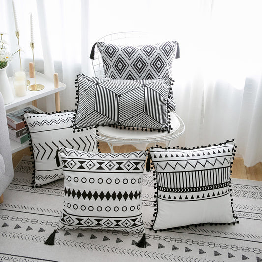 Black and white patterned pillows on a chair and floor in a room setting.
