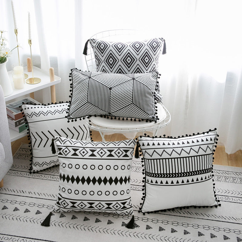 Black and white patterned pillows on a chair and floor in a room setting.