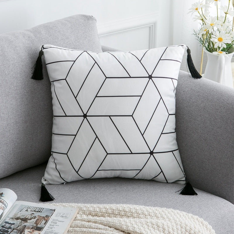 Geometric-patterned pillow with tassels on a gray sofa