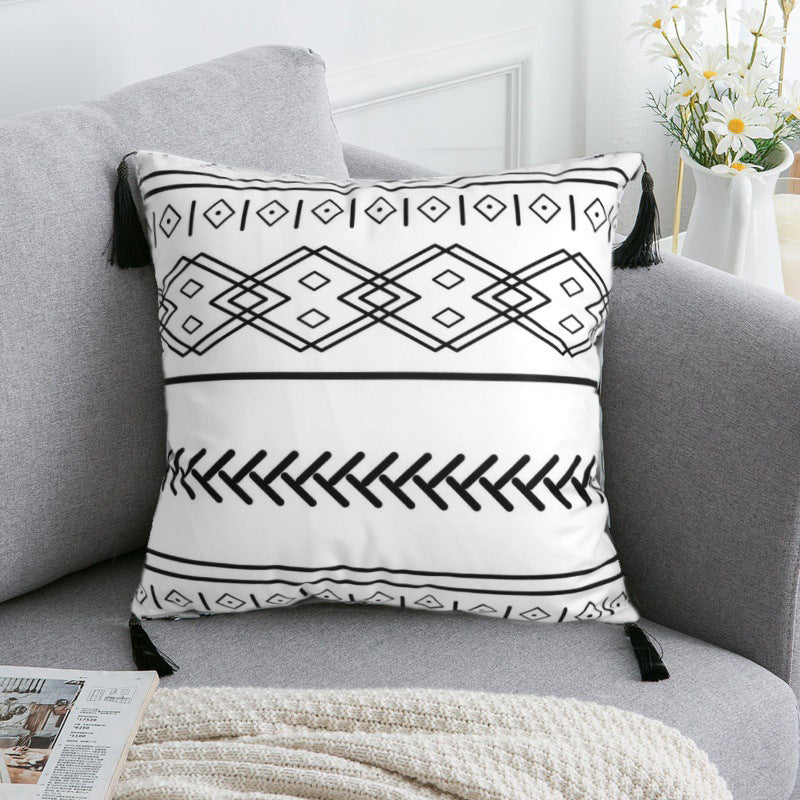 Decorative pillow with black geometric patterns on a gray sofa.