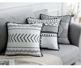 Decorative pillows with black and white patterns on a gray sofa.