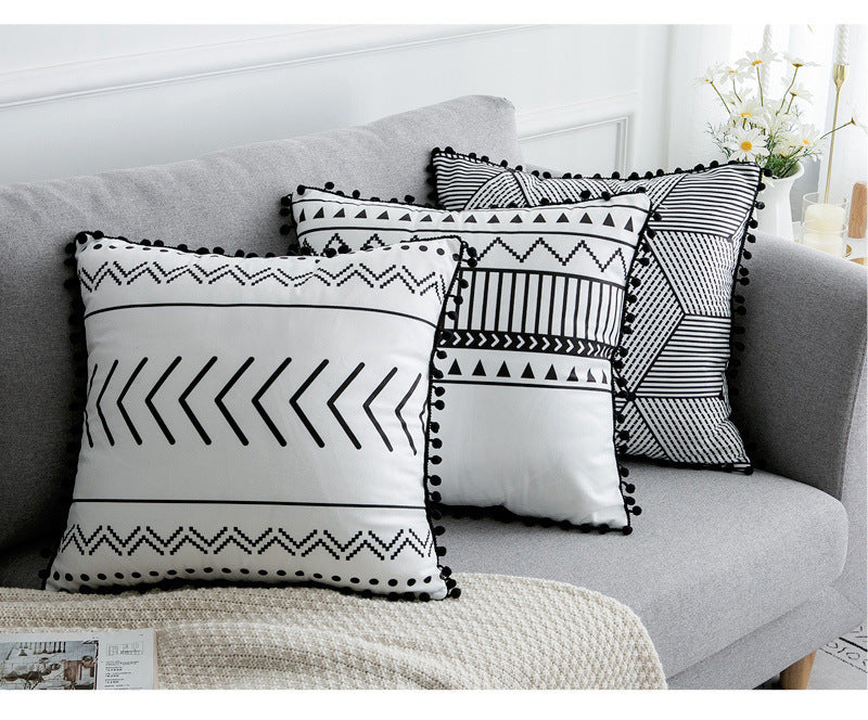 Decorative pillows with black and white patterns on a gray sofa.
