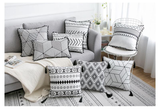Decorative pillows with geometric patterns on a sofa and chair in a living room setting.