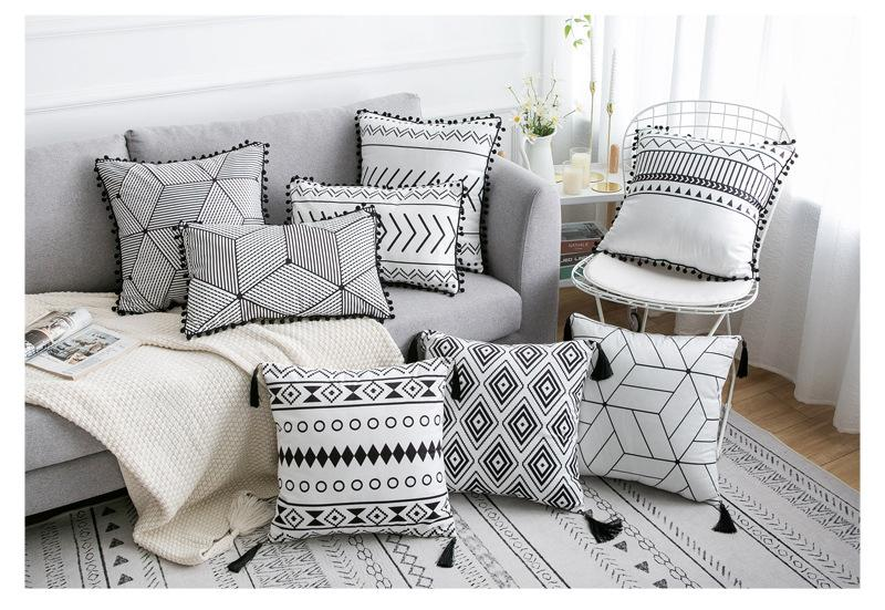 Decorative pillows with geometric patterns on a sofa and chair in a living room setting.