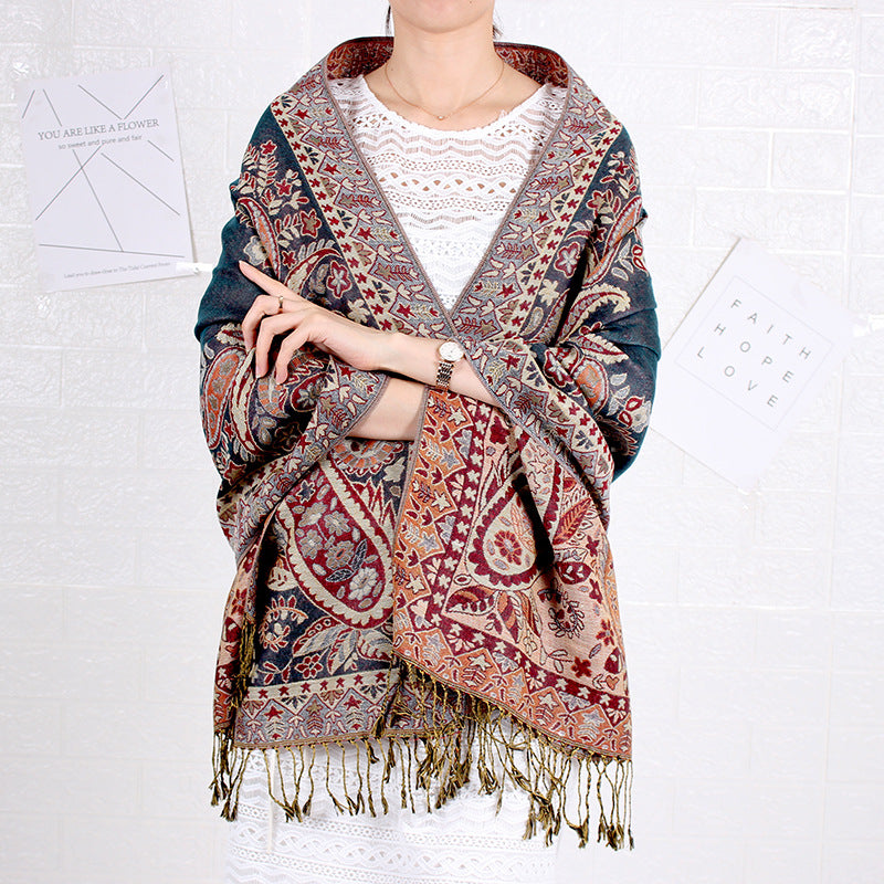 Person wearing a patterned shawl with fringes on a white background