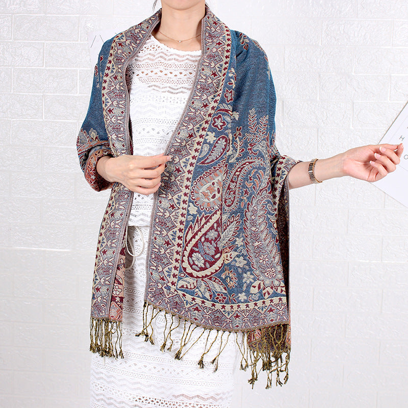 Person wearing a patterned scarf with fringes on a white background