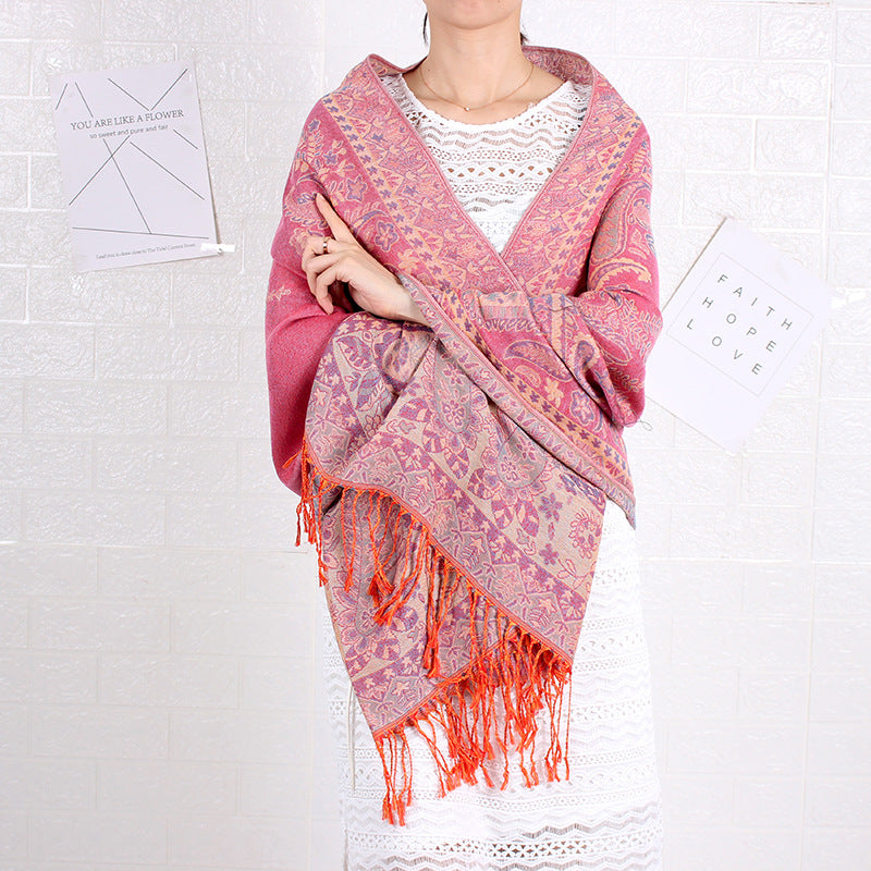 Person wearing a pink patterned shawl with orange fringes on a white background