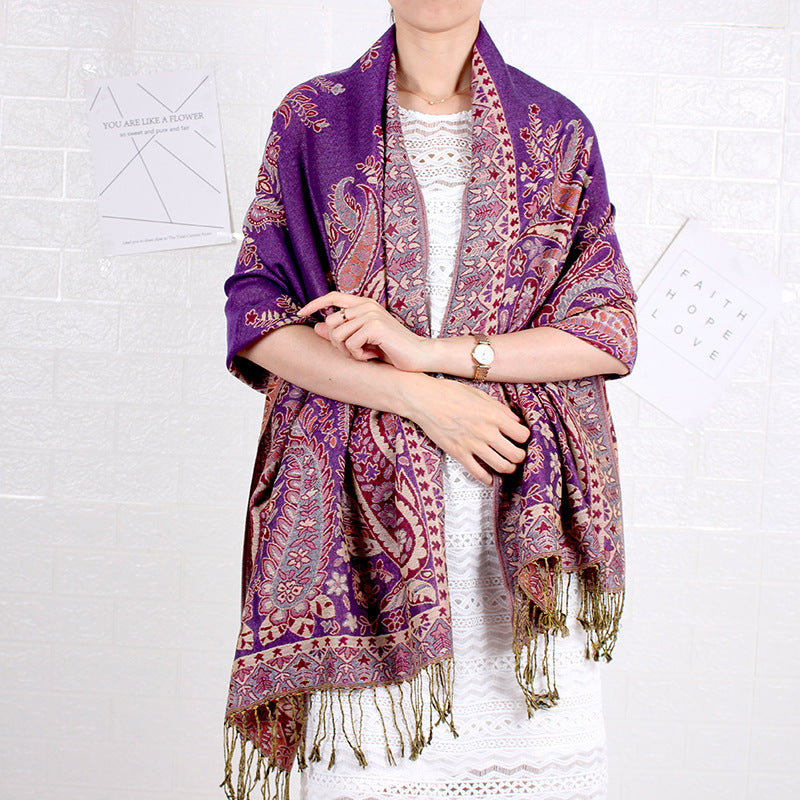 Person wearing a purple patterned scarf with tassels on a white background