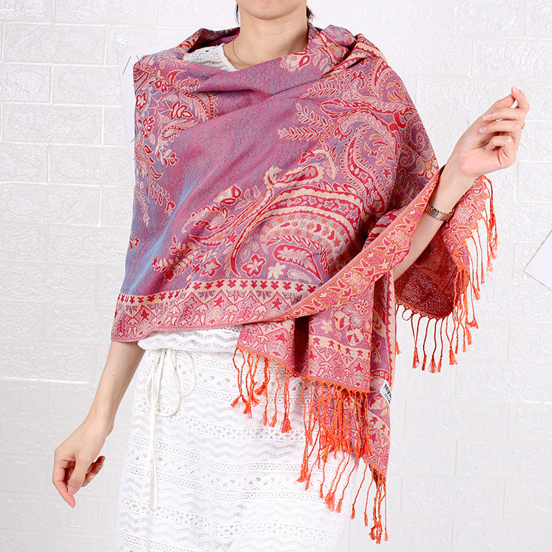 Person wearing a pink and red patterned scarf with fringes on a white background