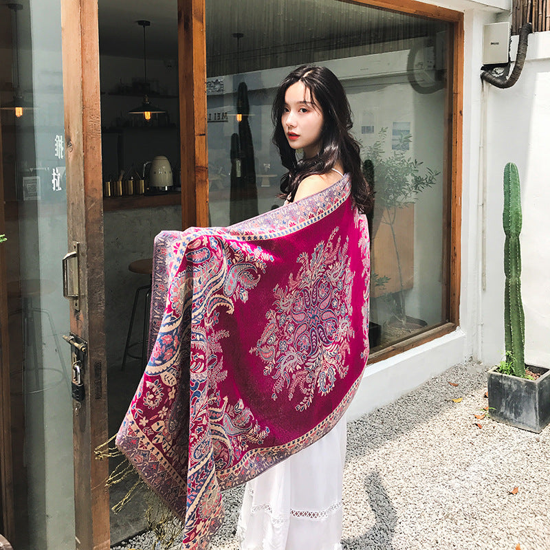 Woman holding a large pink and white patterned scarf in front of a glass door.
