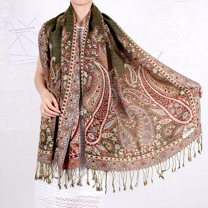 Patterned scarf with fringes draped over a person on a white background