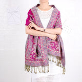 Person wearing a pink and purple patterned scarf with fringes on a white background