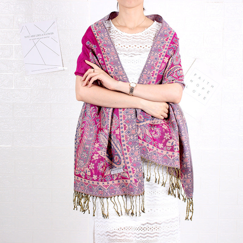 Person wearing a pink and purple patterned scarf with fringes on a white background