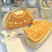 Two cat-shaped pouches on a desk with stationery items.