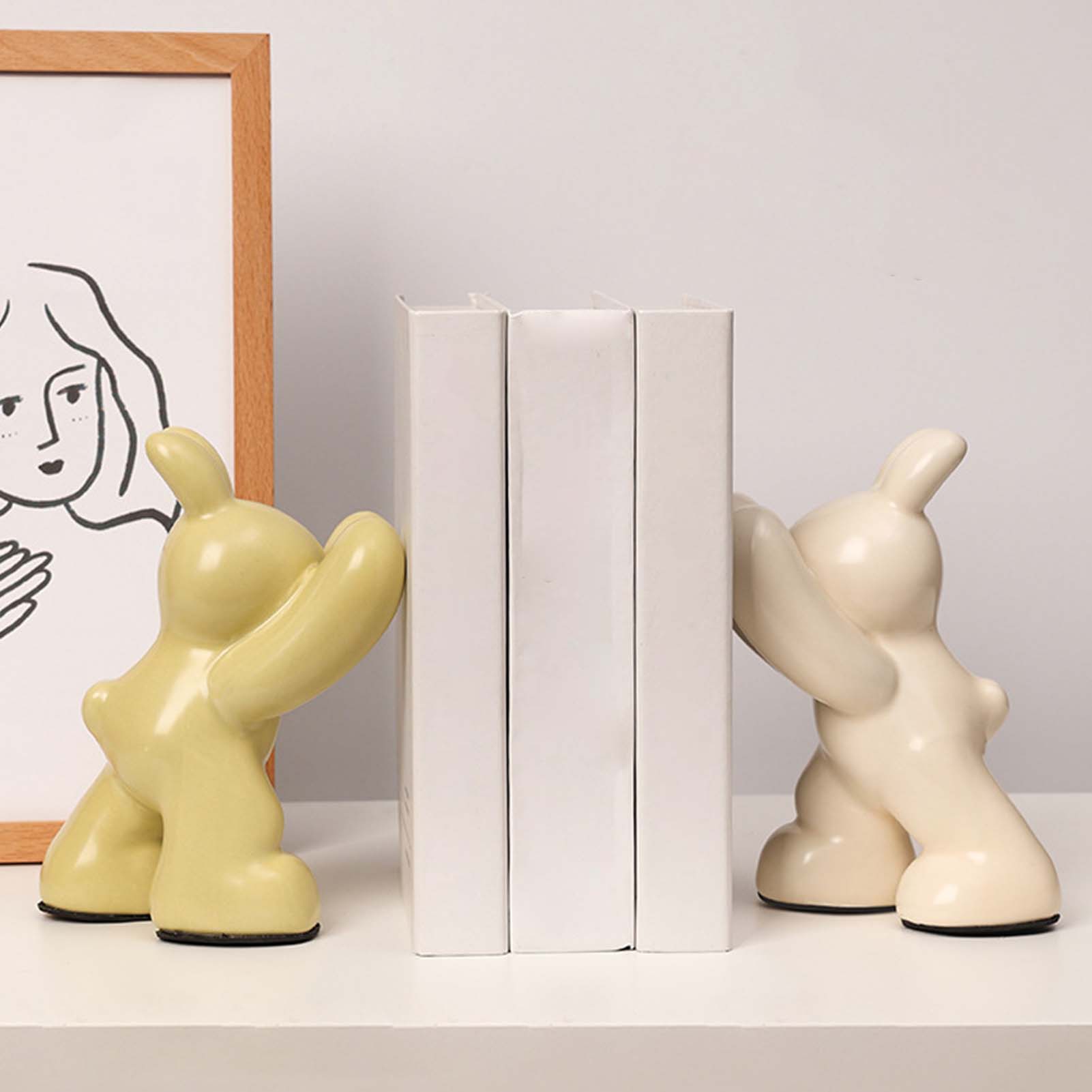 Two ceramic bookends shaped like abstract figures on a shelf with a minimal background.