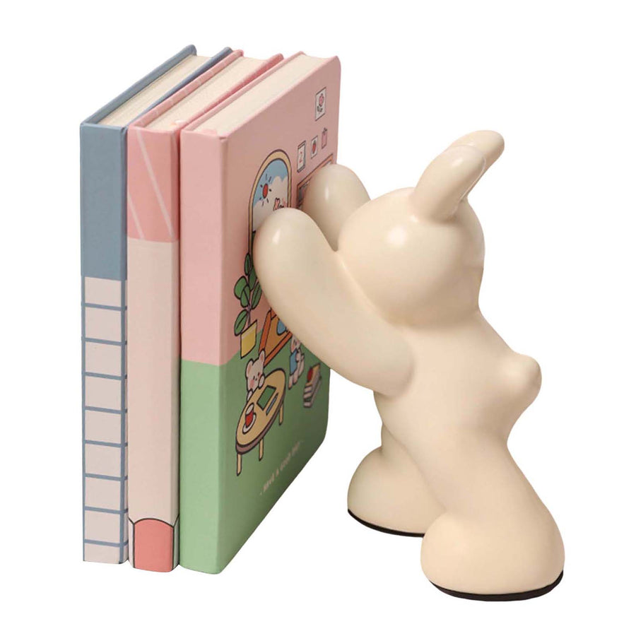 Unicorn-shaped bookend holding three books on a white background