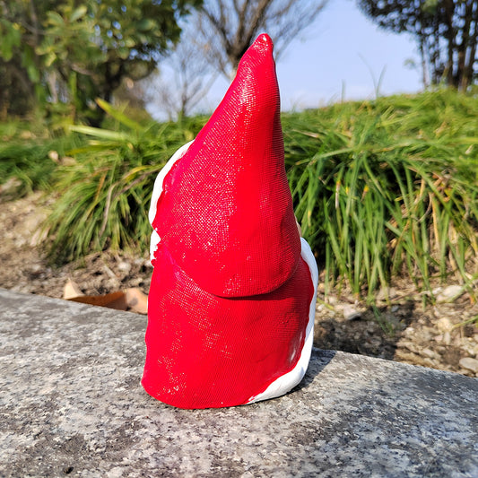 Red gnome figure on a stone surface with greenery in the background