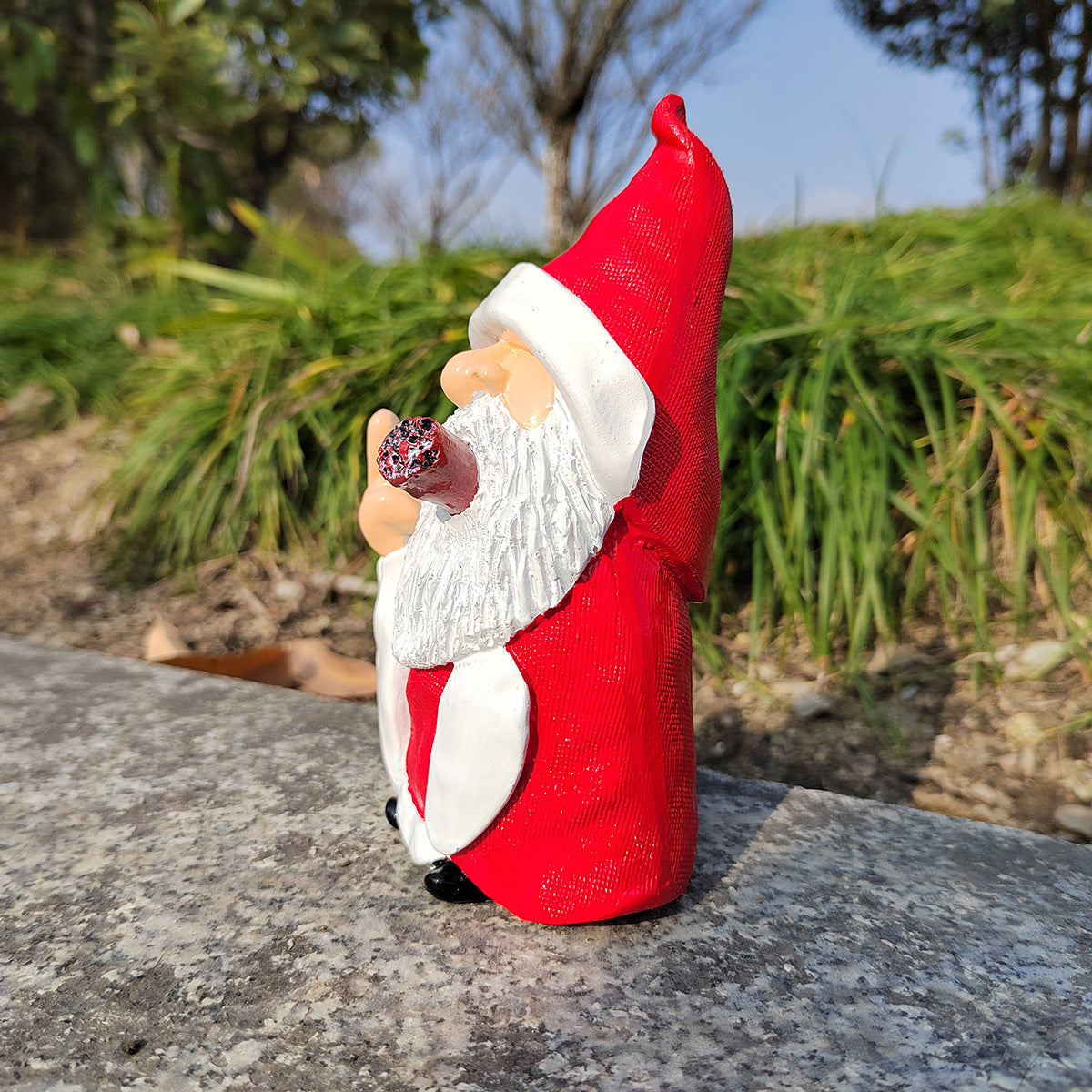 Red gnome figurine with a white beard standing on a stone surface outdoors.