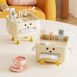 Two beige cartoon-style tissue holders with various items on a table next to a cup of coffee.