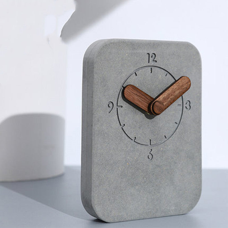 Concrete clock with wooden hands on a light gray surface