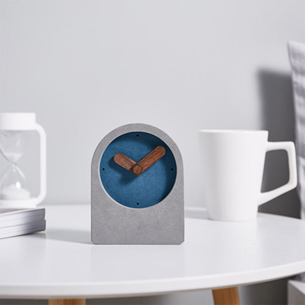 Small clock with blue face and wooden hands on a white surface