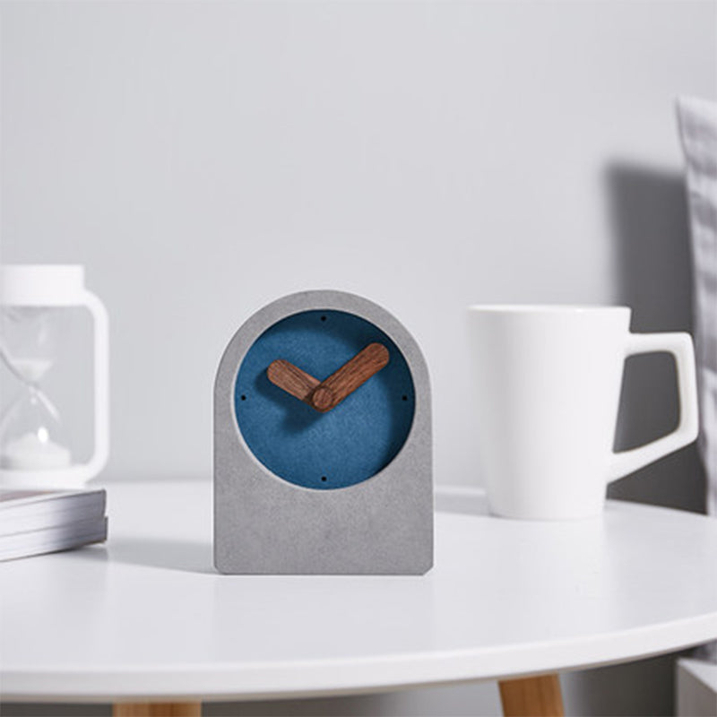 Small clock with blue face and wooden hands on a white surface