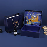 Decorative box with artistic design, black bottle, and gold ribbon on a blue background