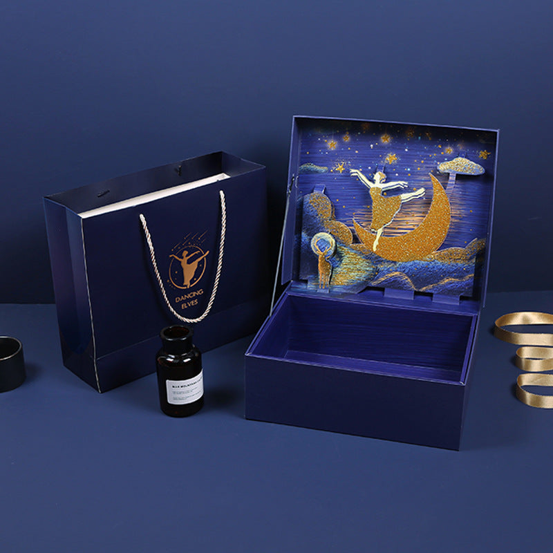 Decorative box with artistic design, black bottle, and gold ribbon on a blue background