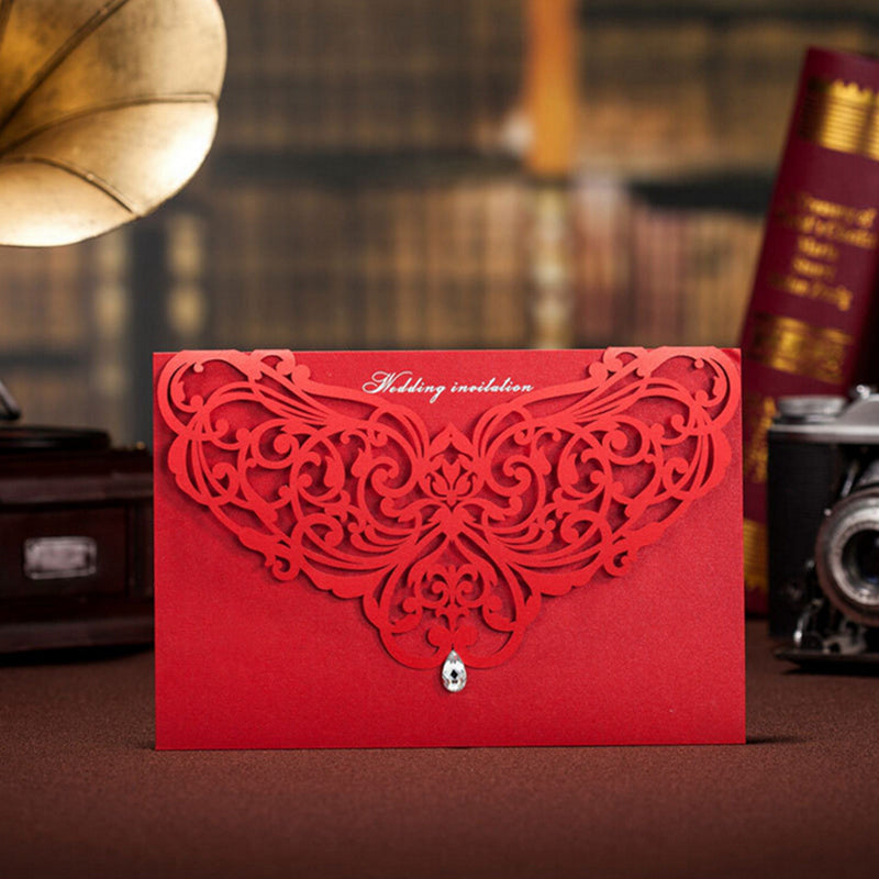 Red wedding invitation card with intricate design on a blurred background