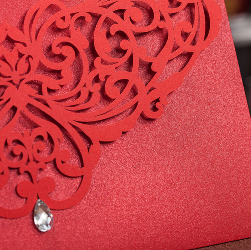 Red decorative card with intricate cut-out design and a crystal embellishment.