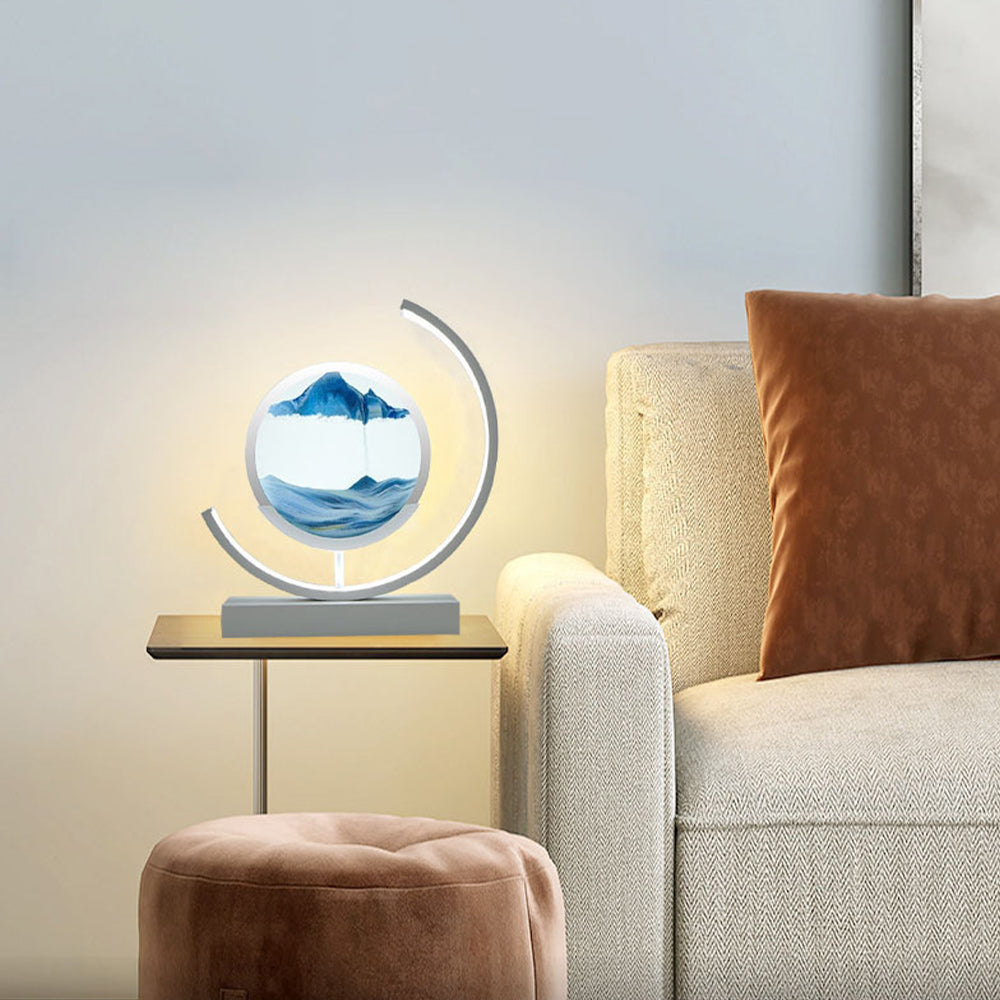 Decorative lamp with mountain design on a side table next to a sofa.