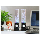 Two colorful water lamps on a desk with a laptop and small figurine.
