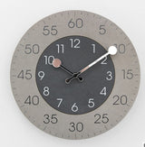 Round wall clock with gray casing and black face on a white background