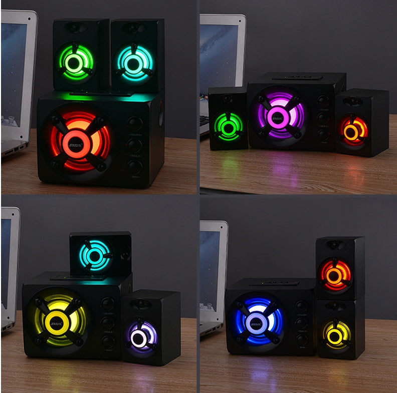 Colorful LED light-up speakers on a desk with laptops in the background