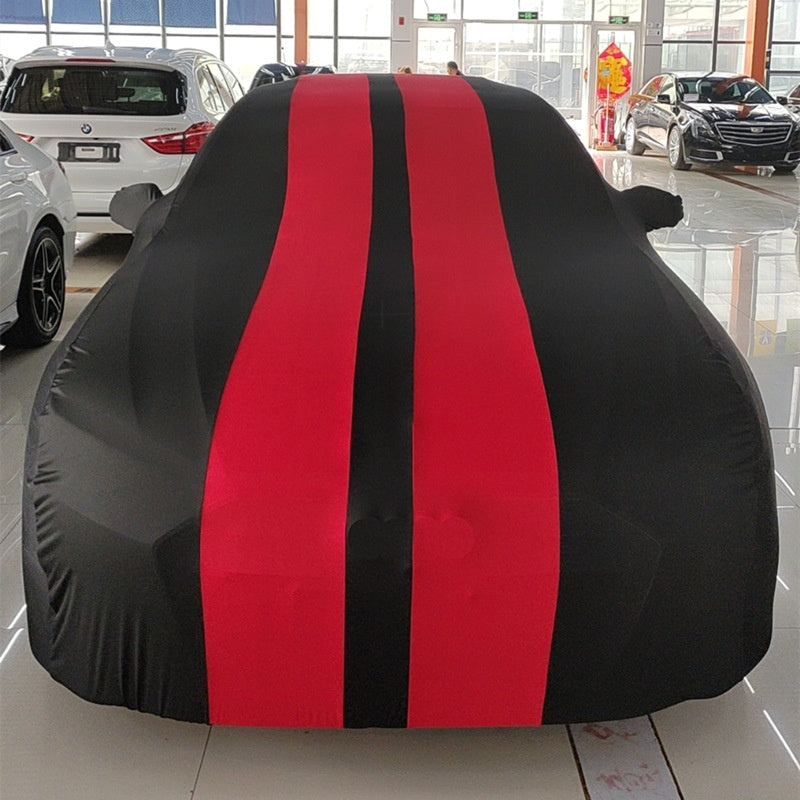 Car covered with a black and red striped cover in a showroom.