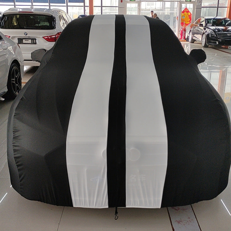 Car covered with a black and white striped car cover in a showroom.