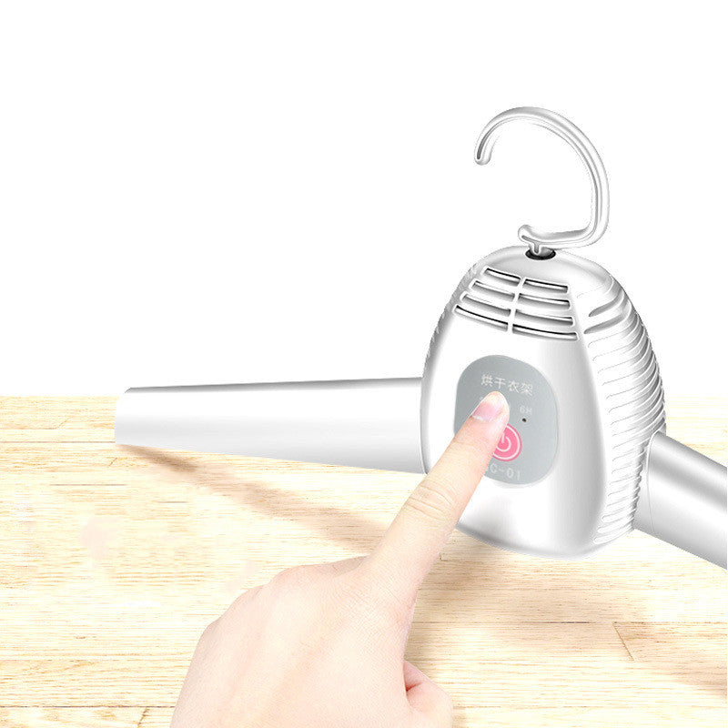 Handheld garment steamer with a hand pressing a button on a wooden surface