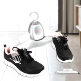 Black sneakers being dried with a portable shoe dryer on a white background