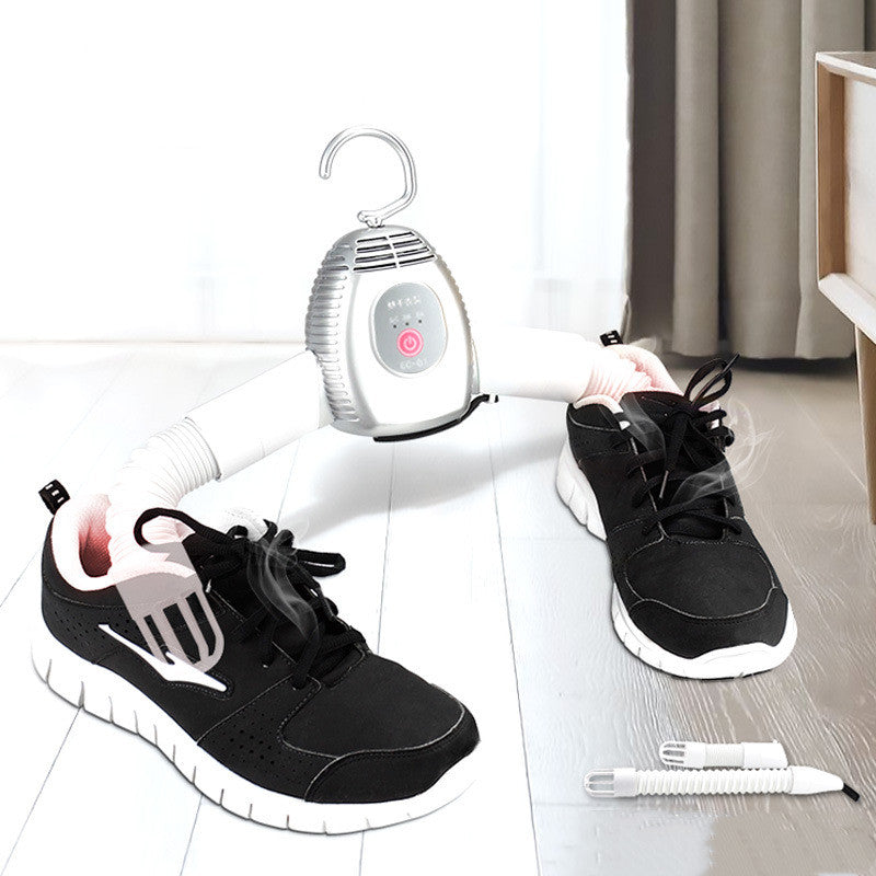 Black sneakers being dried with a portable shoe dryer on a white background