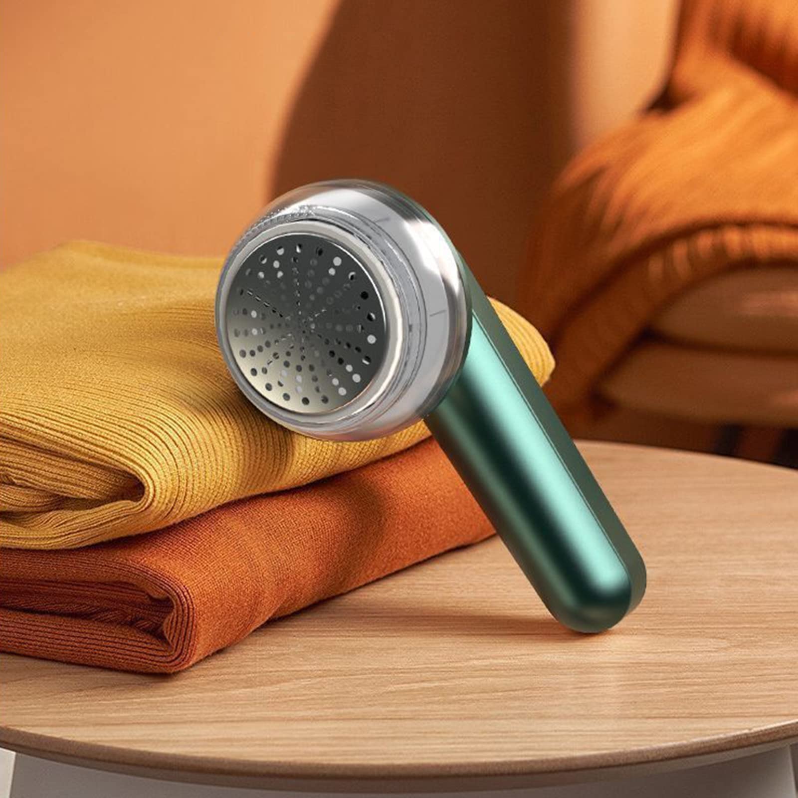 Handheld fabric shaver on a stack of clothes with a blurred background